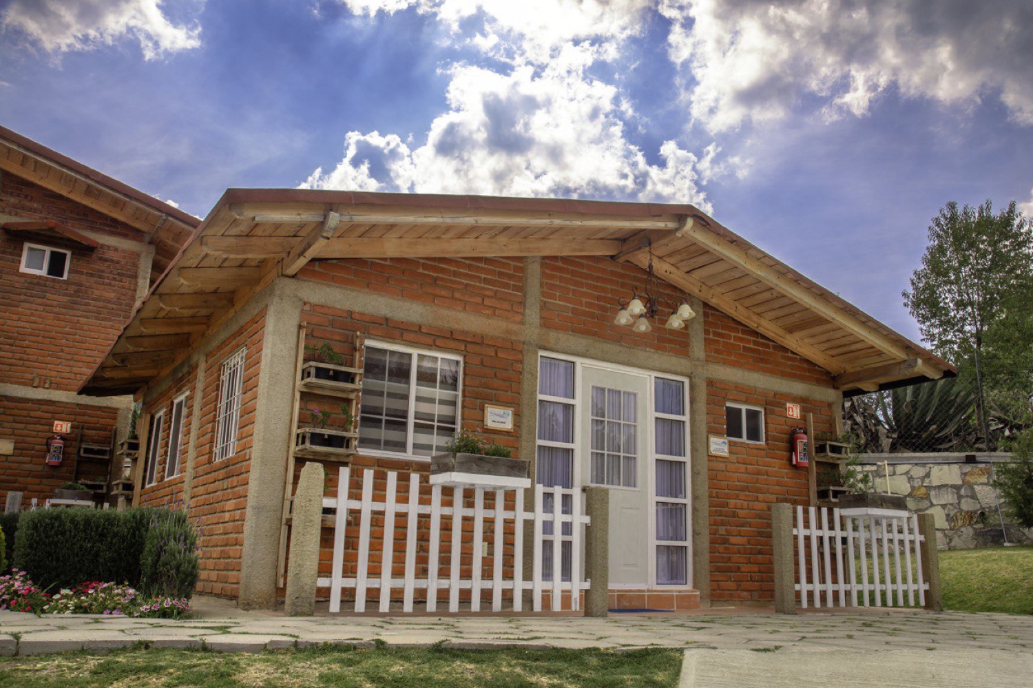 Fachada de la Cabaña La Rica, de un nivel, en ladrillo y madera