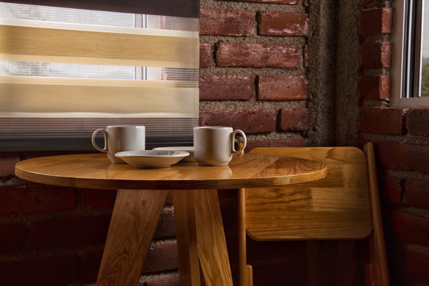 Detalle de mesa de madera con tazas de café junto a la ventana