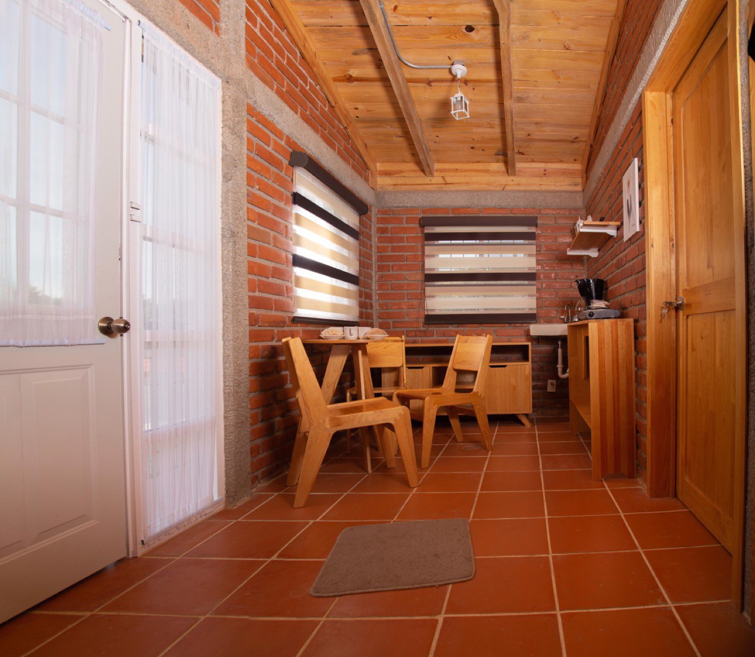 Cocina y comedor de la cabaña con muros de ladrillo